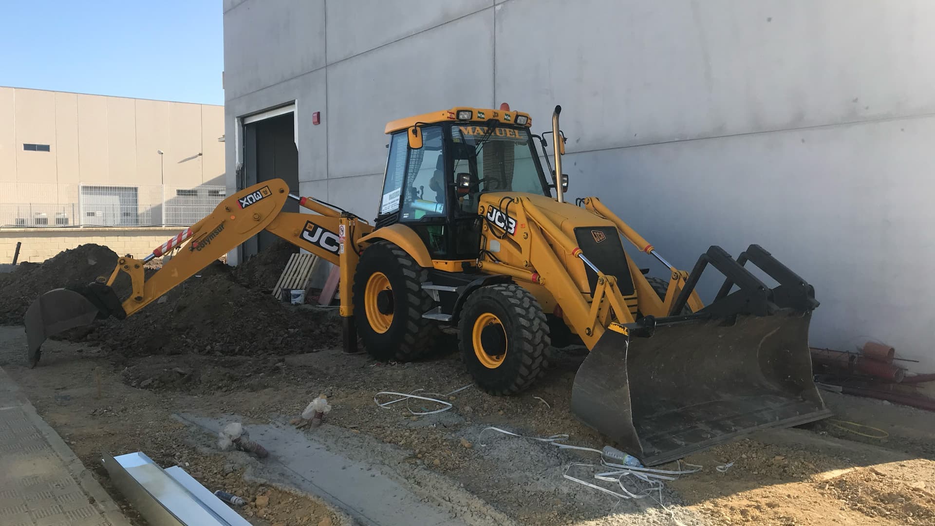 Retroexcavadora JCB junto a nave
